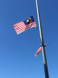 Low angle view of flag flags against clear blue sky