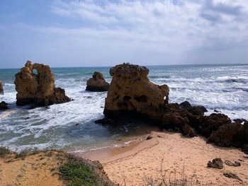 Rock formation on beach against sky