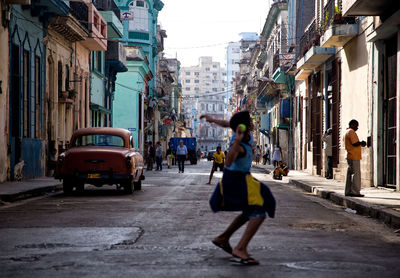Woman walking on street in city against sky