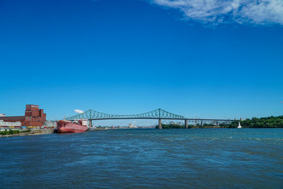 Suspension bridge over river against blue sky