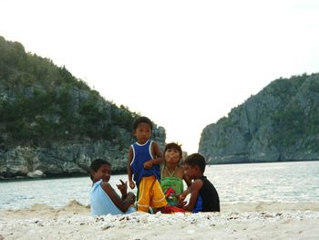 Portrait of children playing on beach against sky