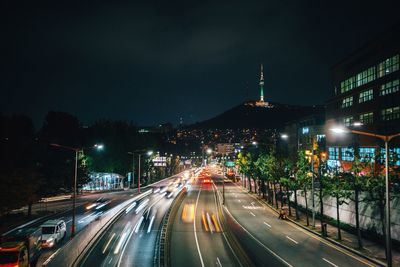 Distant view of n seoul tower with city street in foreground at night