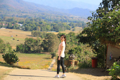 Full length portrait of woman standing against landscape