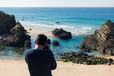 Rear view of man standing on rocks at beach