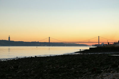 View of suspension bridge over river at sunset