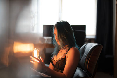 Woman using phone while sitting on window