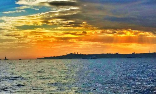 Scenic view of sea against cloudy sky at sunset