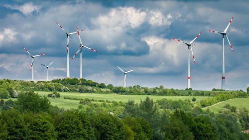 Wind turbines on field against sky