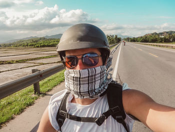 Portrait of man wearing sunglasses on road against sky