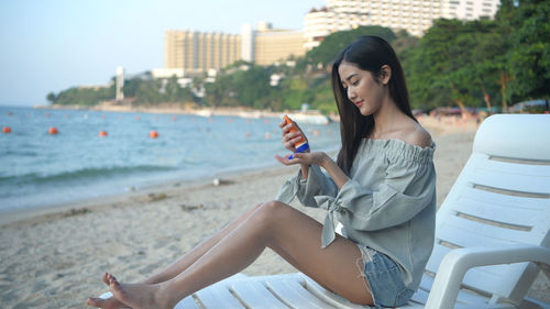 Young woman using mobile phone while sitting on land