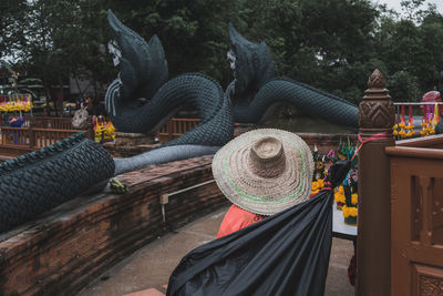 Person wearing hat while standing against black animal statues