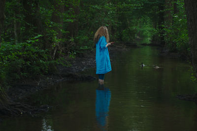 Woman standing in river at forest