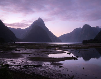 Purple sunset in fiords with reflections on water surface.milford sound,fiordland np, new zealand