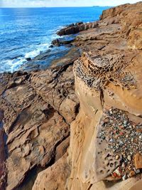 Rock formation on beach against sky