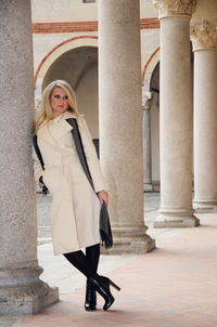 Full length portrait of woman standing against built structure