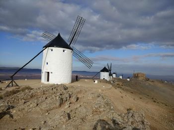 Traditional windmill on beach against sky