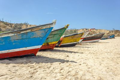 Boats moored on beach against clear sky