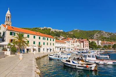 Sailboats moored in sea against buildings in city