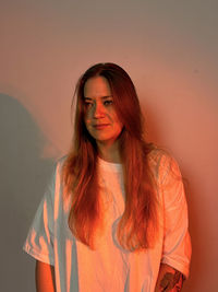 Portrait of young woman standing against wall