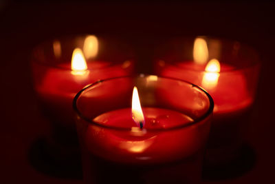 Close-up of lit tea light candles in darkroom