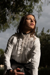 Young woman standing against trees