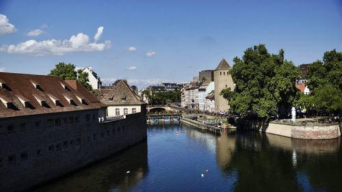 Arch bridge over river amidst buildings against sky