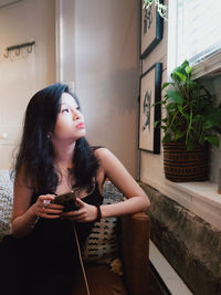 Young woman looking away while sitting in kitchen