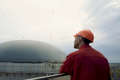 Rear view of man looking at camera against sky