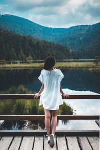 Rear view of woman looking at lake against mountains