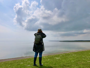 Rear view of man standing by sea against sky