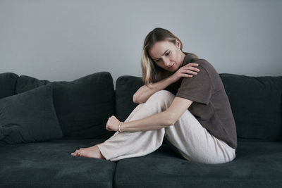Side view of woman sitting on sofa