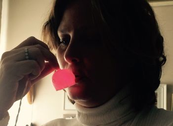 Close-up of woman holding illuminated red lighting equipment at home