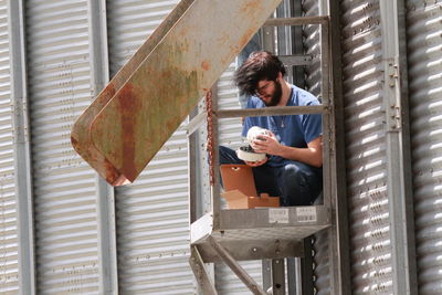 Low angle view of construction worker holding equipment