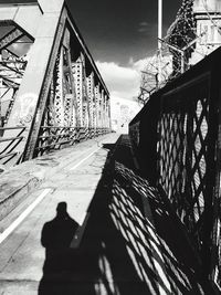 Shadow of person on bridge against sky