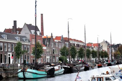 Boats moored at harbor against clear sky