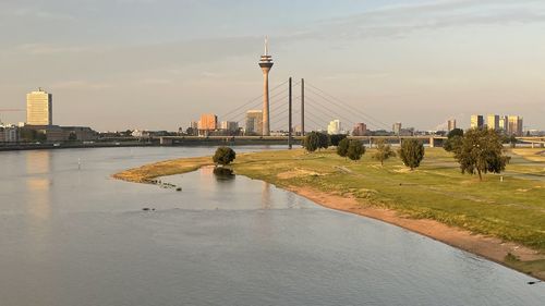 Bridge over river by buildings in city against sky