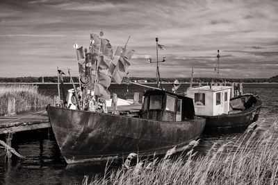 Fishing boats moored on beach against sky