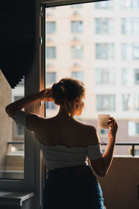 Rear view of woman standing against window