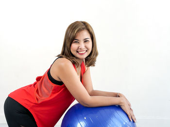 Portrait of a smiling young woman sitting against white background