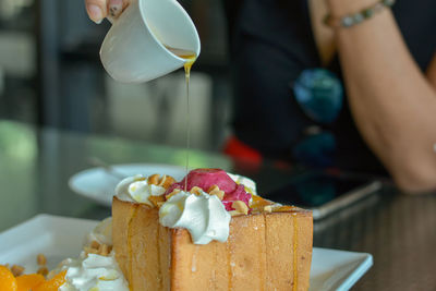 Pour honey on honey toast with red homemade ice cream and whipping cream topping serve with orange.