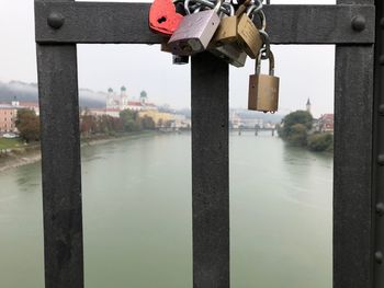 Close-up of padlocks hanging on bridge over river