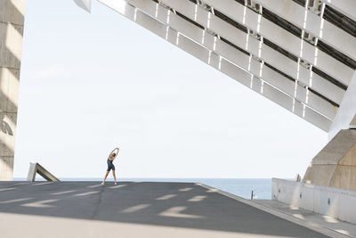 Side view of woman standing by building against sky