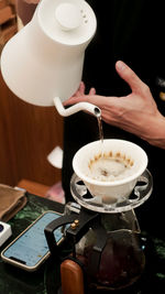 Cropped hand of woman holding coffee on table