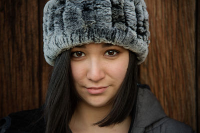 Close-up portrait of teenage girl wearing hat against wall
