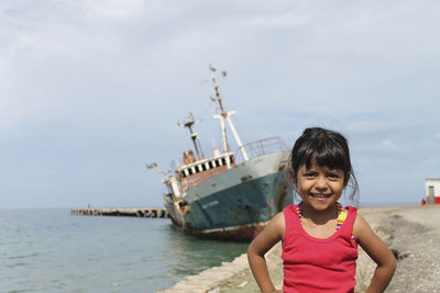 Portrait of girl standing at beach against sky