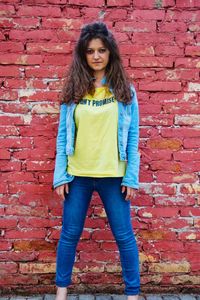 Portrait of beautiful woman standing against brick wall