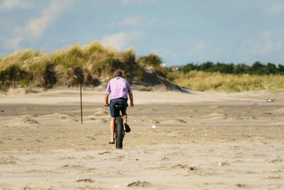 Rear view of man riding bicycle on road