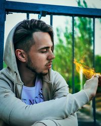 Close-up if man with burning hand against railing