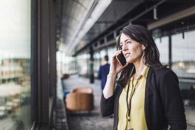 Female entrepreneur talking on smart phone while standing at workplace