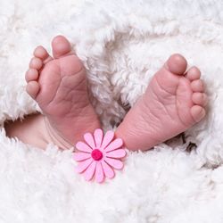 Low section of baby feet on bed at home